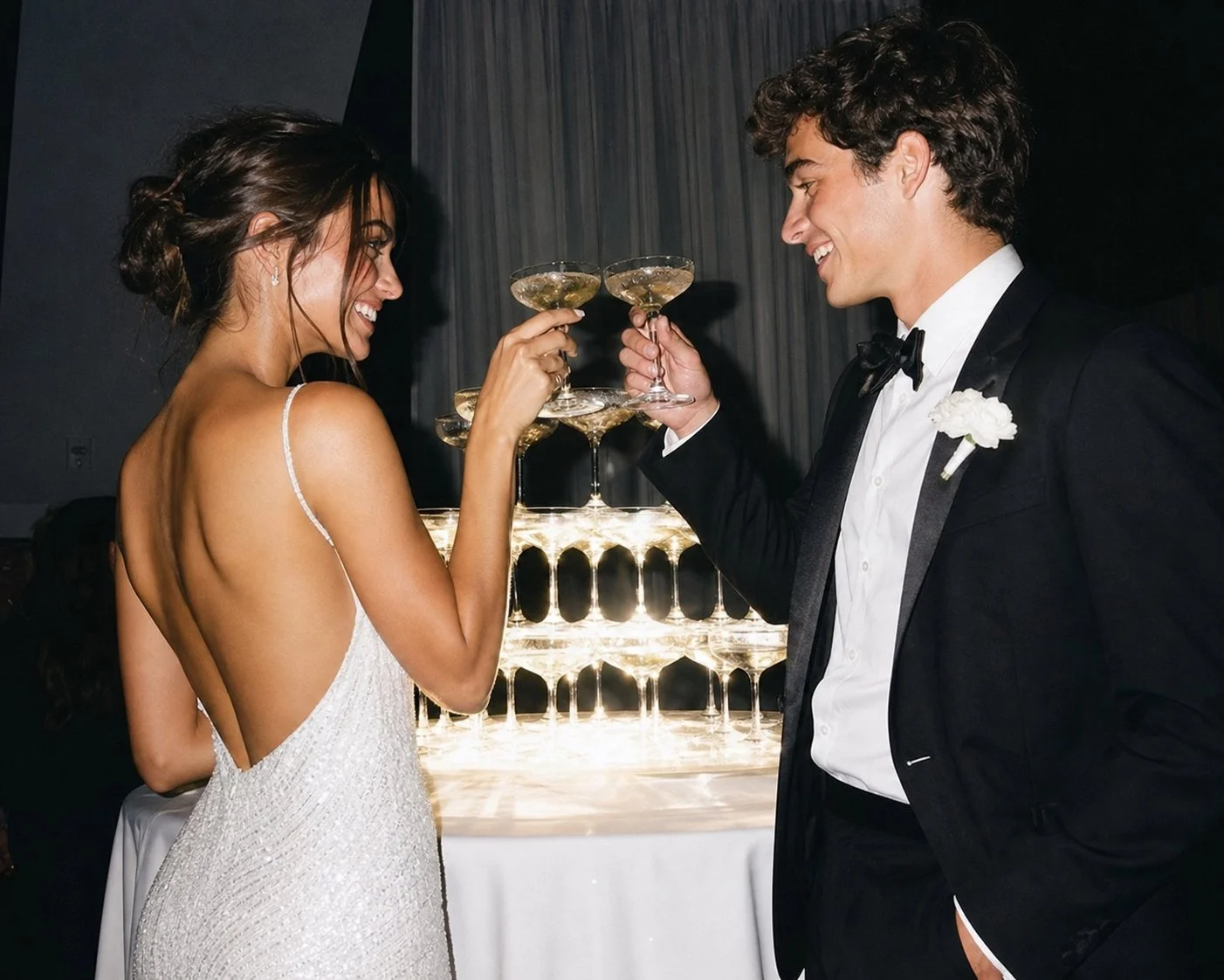 Gen-Z wedding afterparty reception newlywed couple toasting champagne glasses next to glowing champagne tower